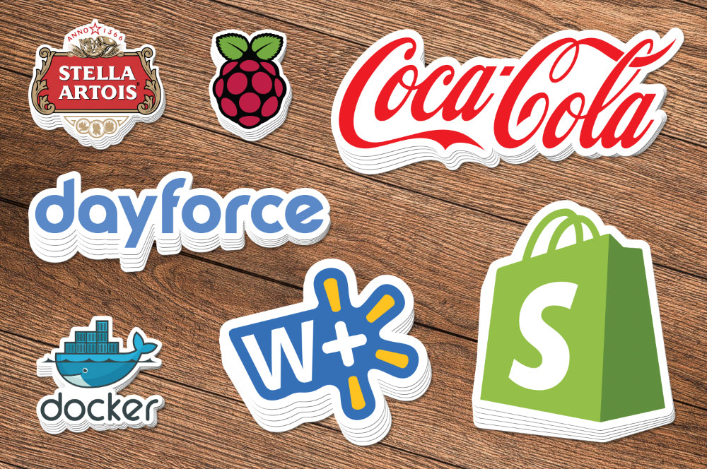 Assorted branded die-cut stickers displayed on a wooden surface, showcasing high-quality cuts.