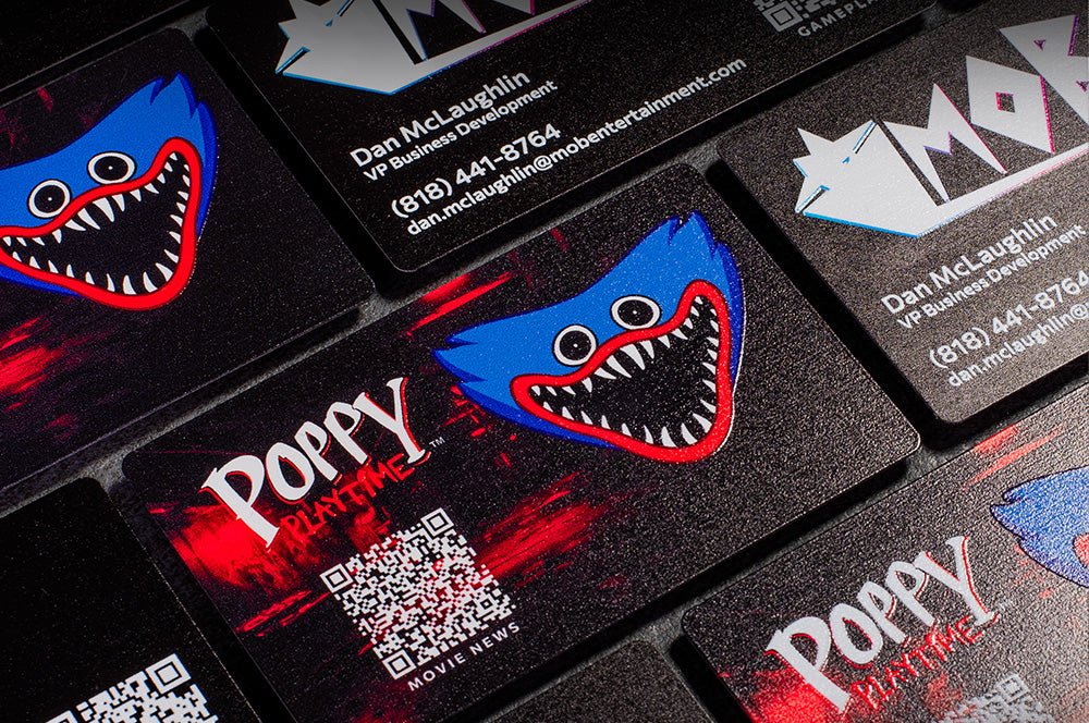 Custom aluminum business cards for MOB Entertainment featuring vibrant Poppy Playtime graphics, QR codes, and premium black metal finish.