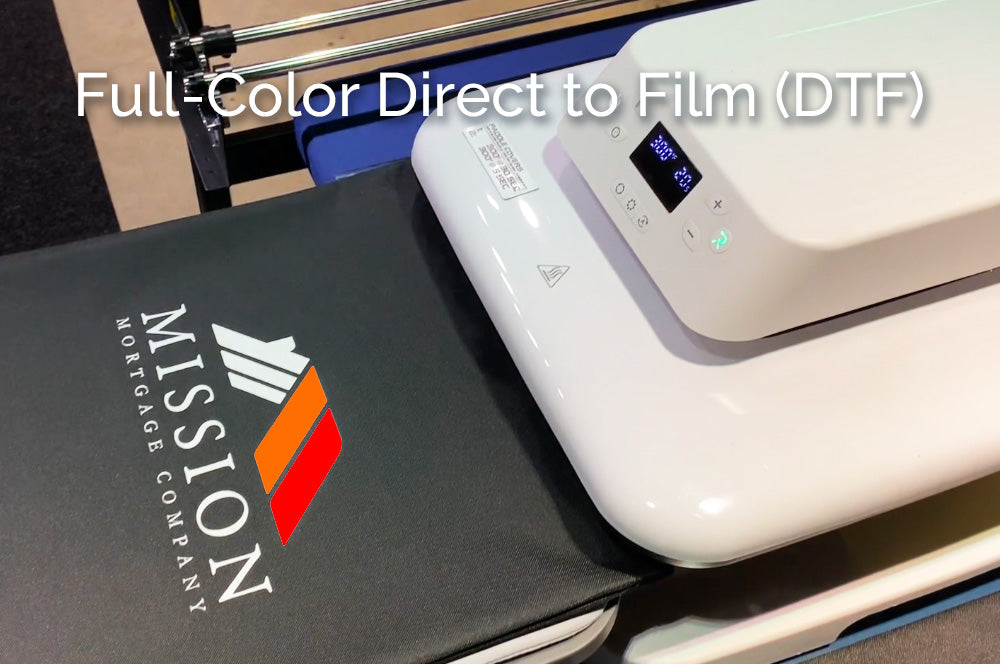 DTF heat press applying a full-color logo to a black tote bag using Direct to Film printing technology
