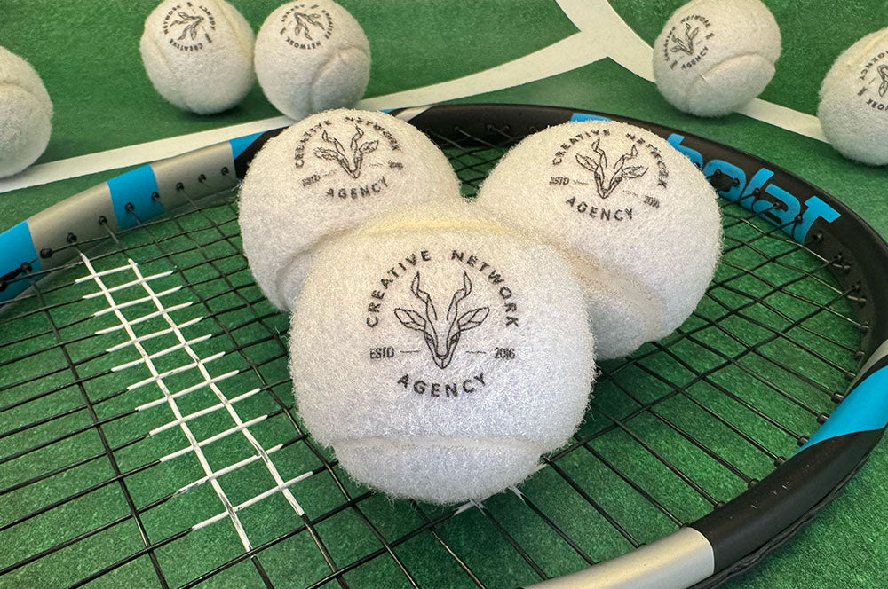 White branded tennis balls featuring a custom logo, designed for creative promotional use.