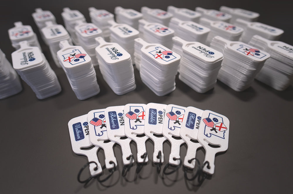 Multiple white plastic tags with logos on a dark surface
