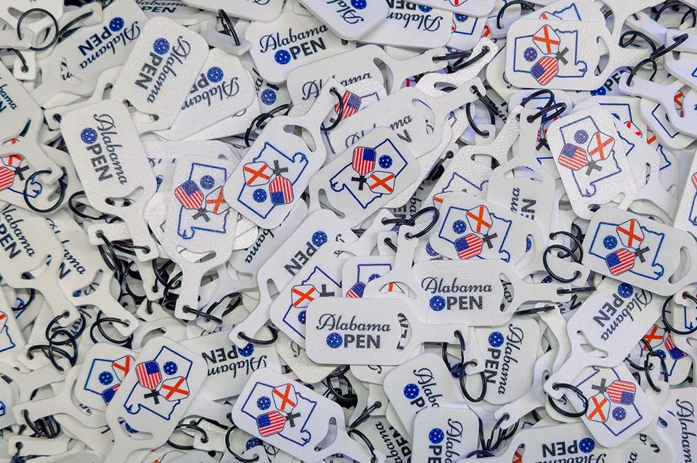 Collection of Alabama Open event tags with various designs and text.