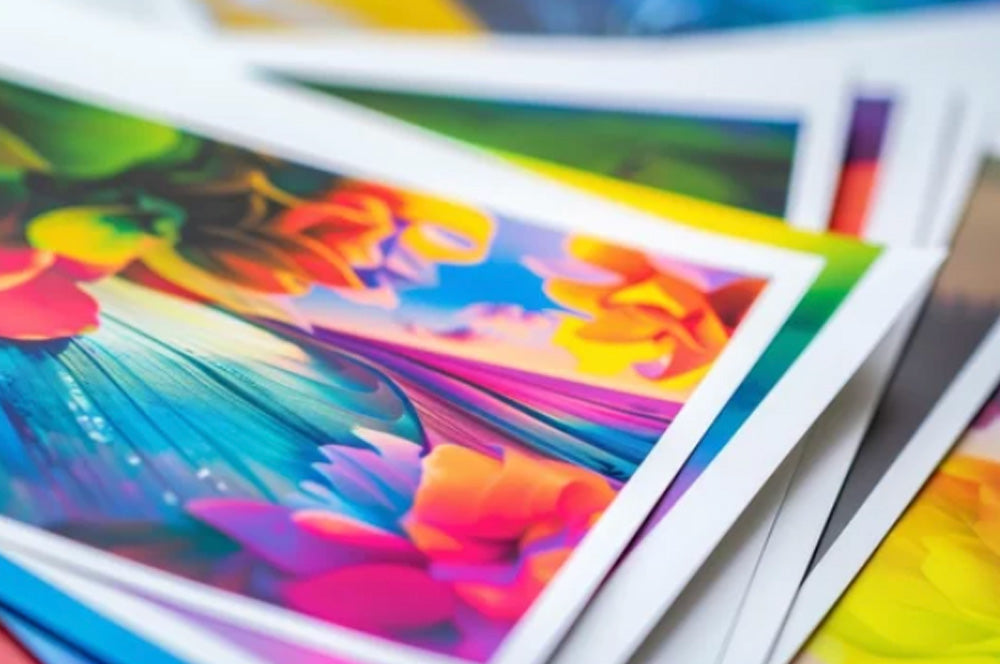 Stack of vibrant large format art prints with colorful floral and abstract designs